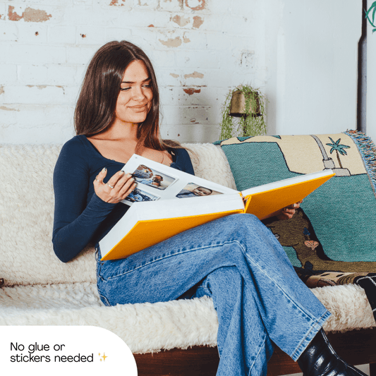 Woman on a sofa flicking through her Mosaic Journal of printed photos
